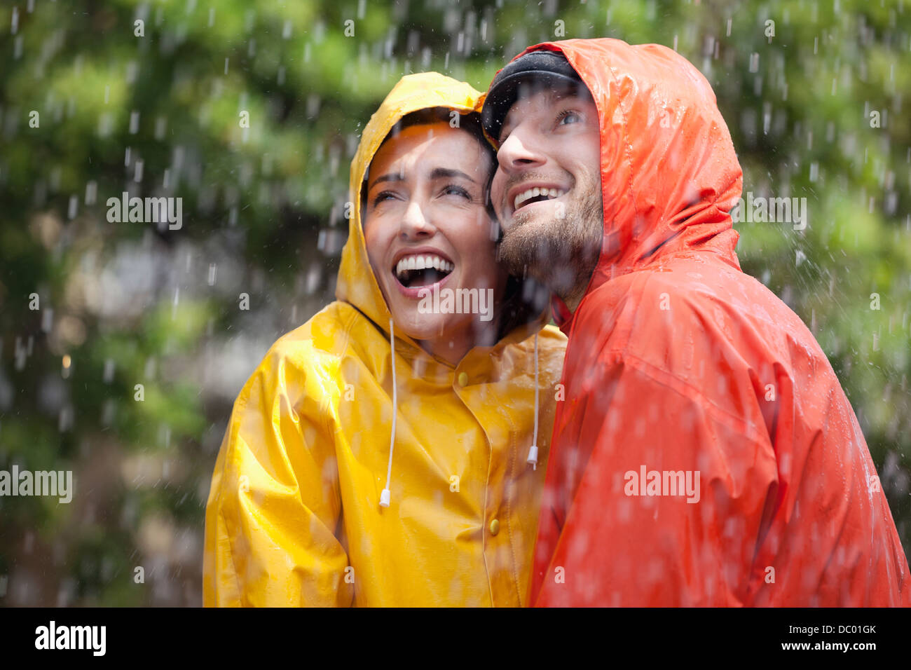 Glückliches Paar in Regenmäntel blickte zu Regen Stockfoto