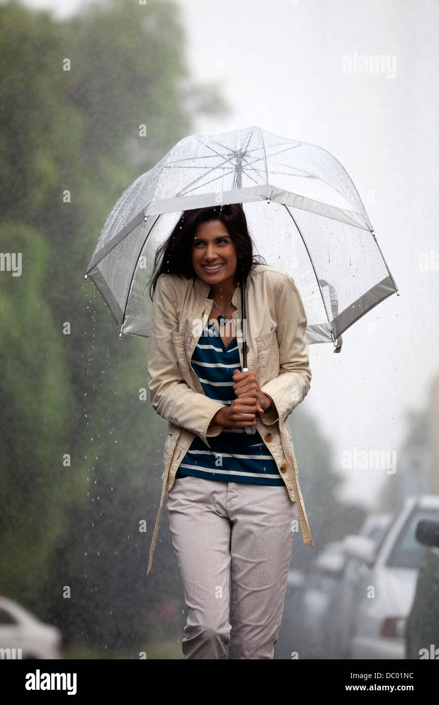 Glückliche Frau unter Dach im Regen Stockfoto