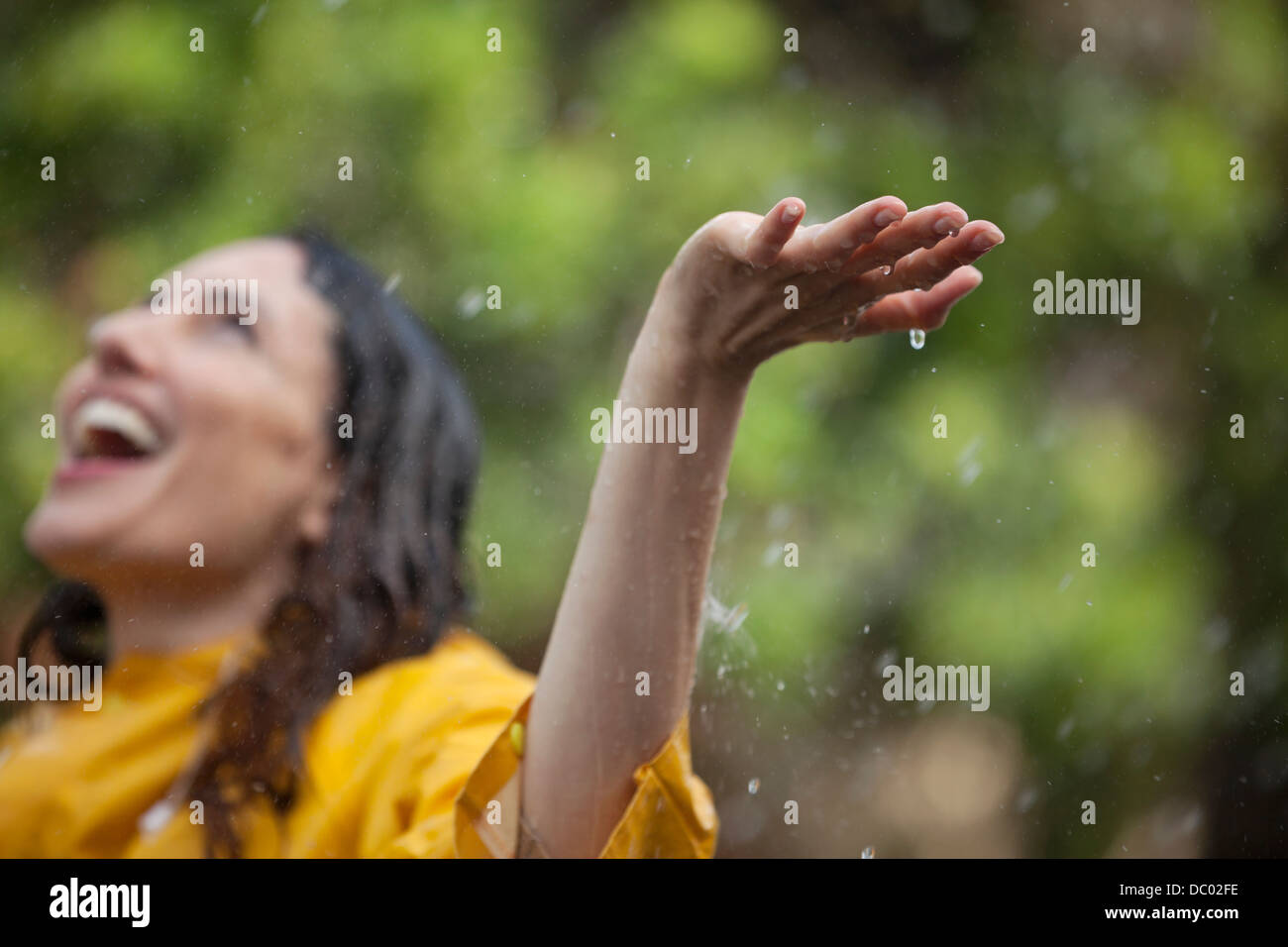 Begeisterte Frau mit ausgestreckten Armen und Kopf zurück in Regen Stockfoto