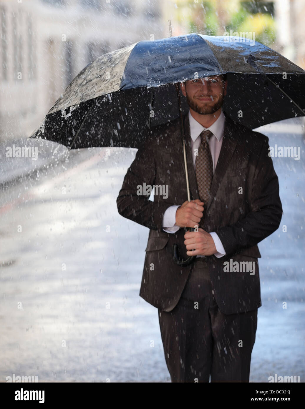 Glücklich Kaufmann mit Regenschirm auf verregnete Straße Stockfoto