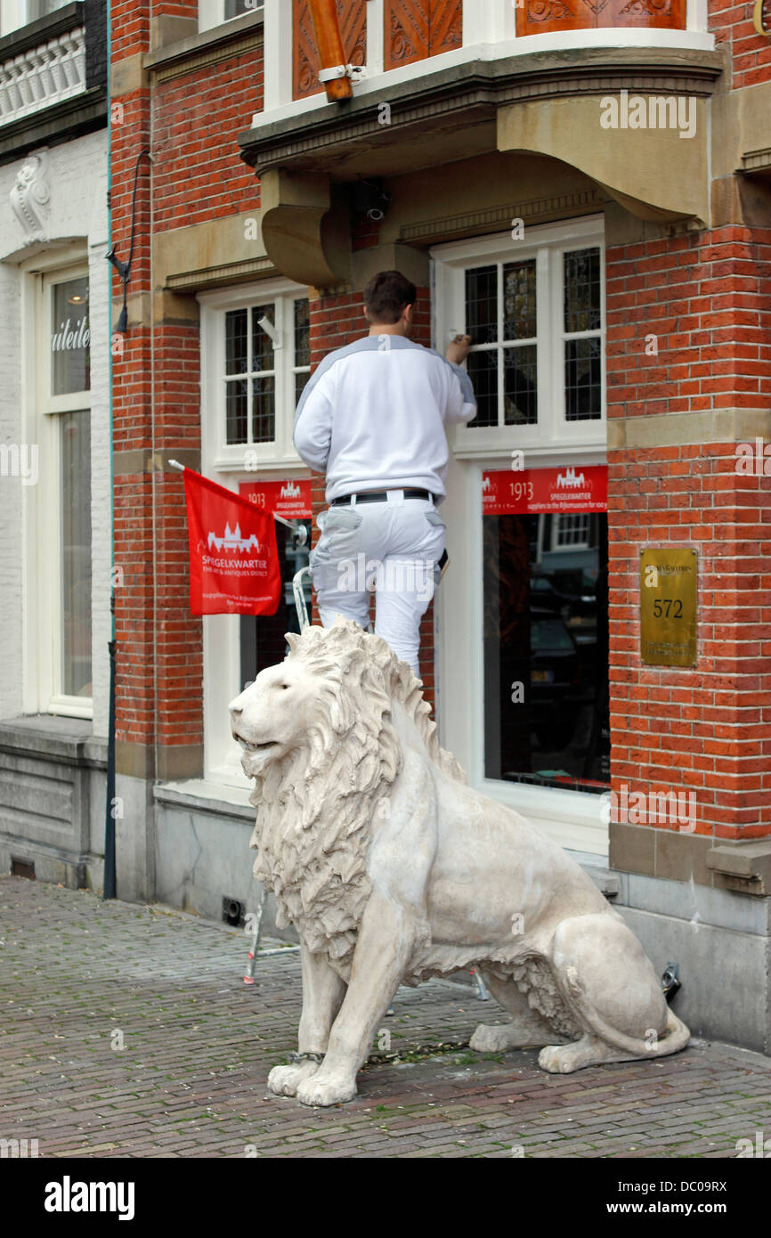Amsterdam Niederlande Holland Europa Mann Malerei Fenster schneiden durch Löwenstatue Stockfoto