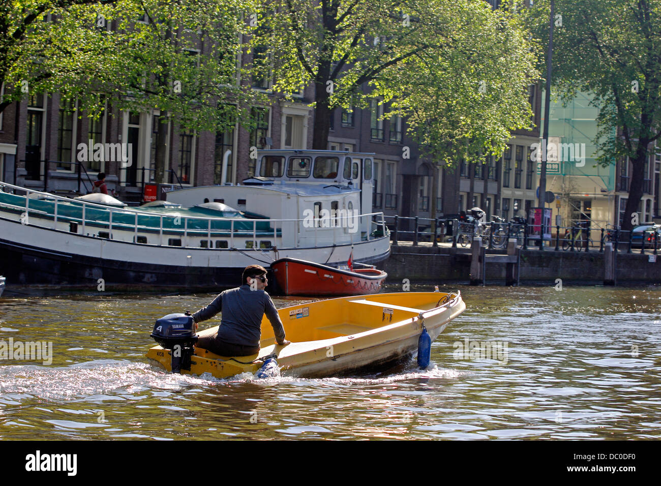 Amsterdam Niederlande Holland Europa Mann im kleinen Boot mit Außenbordmotor entlang der Amstel Kanal Stockfoto