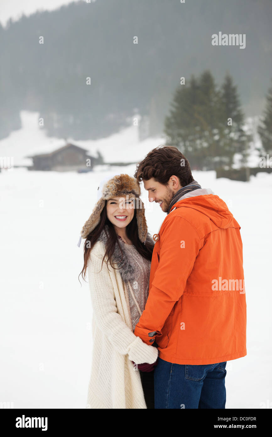 Glückliches Paar halten Hände in schneebedecktes Feld Stockfoto