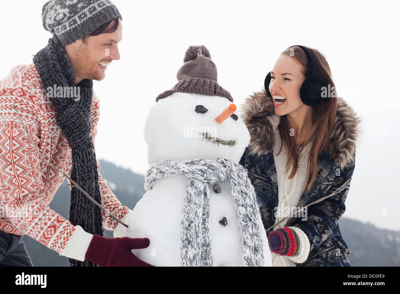 Glückliches Paar machen Schneemann Stockfoto