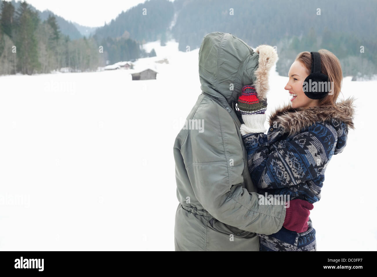 Glückliches Paar umarmt in schneebedecktes Feld Stockfoto