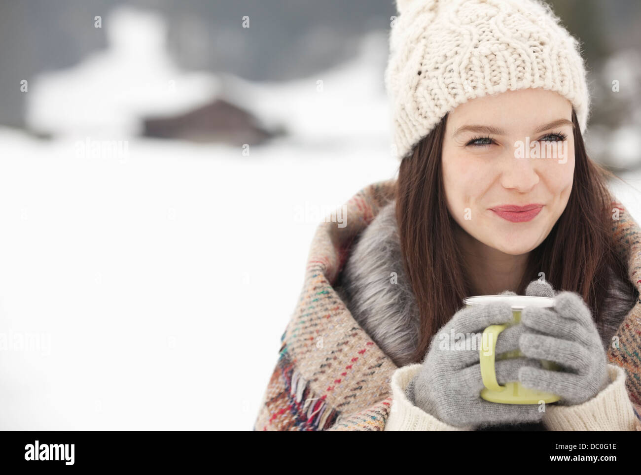 Nahaufnahme der lächelnde Frau in Strick Mütze und Handschuhe Kaffeetrinken in schneebedecktes Feld Stockfoto