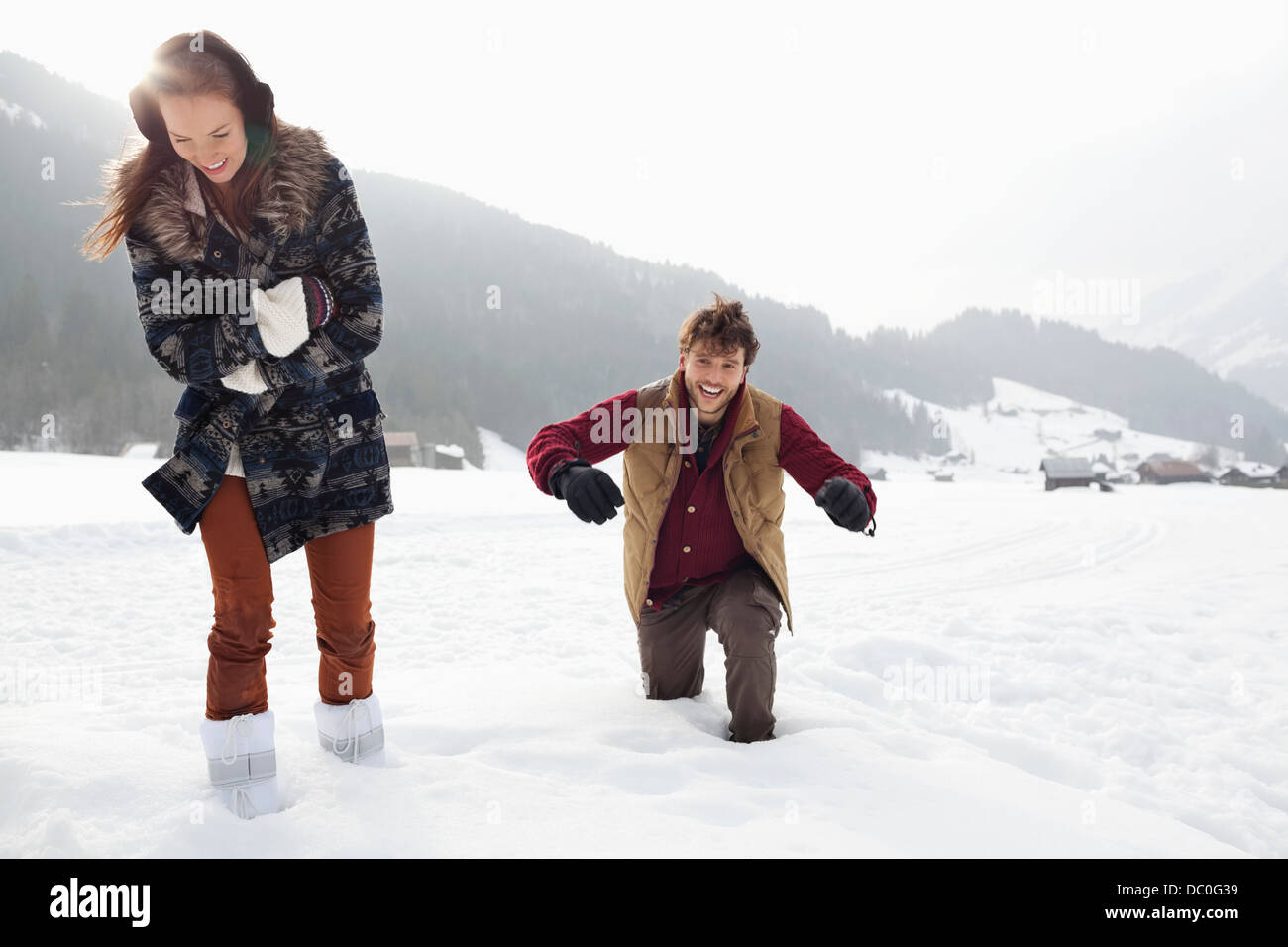 Glückliches Paar zu Fuß durch den Tiefschnee im Feld Stockfoto