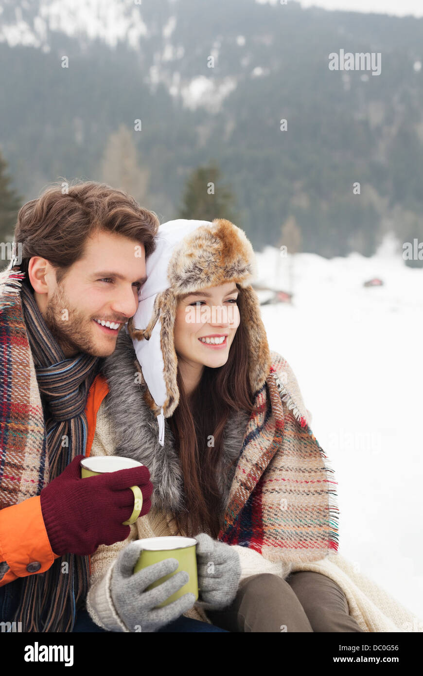 Glückliches Paar Kaffeetrinken in schneebedecktes Feld Stockfoto