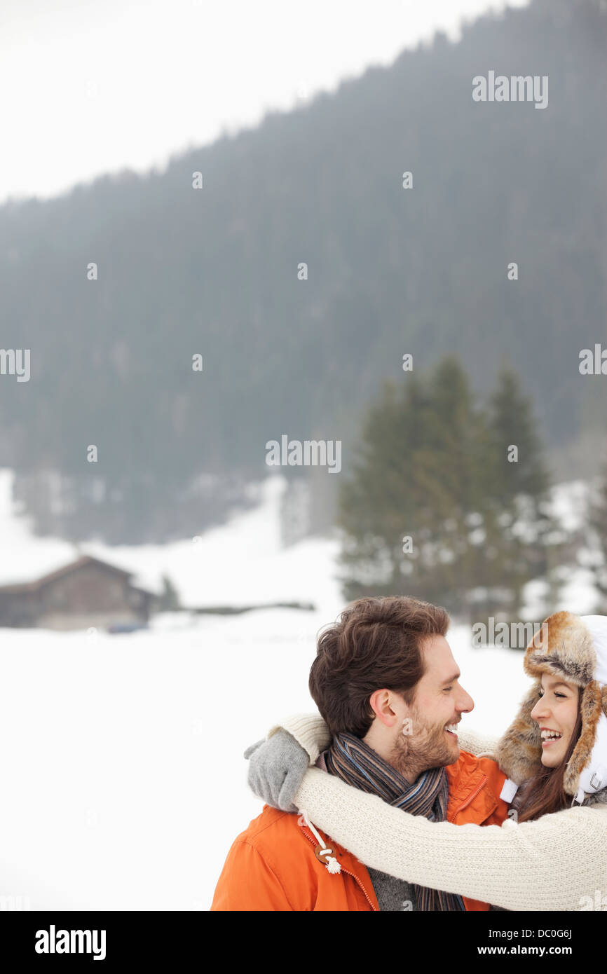 Glückliches Paar umarmt in schneebedecktes Feld Stockfoto