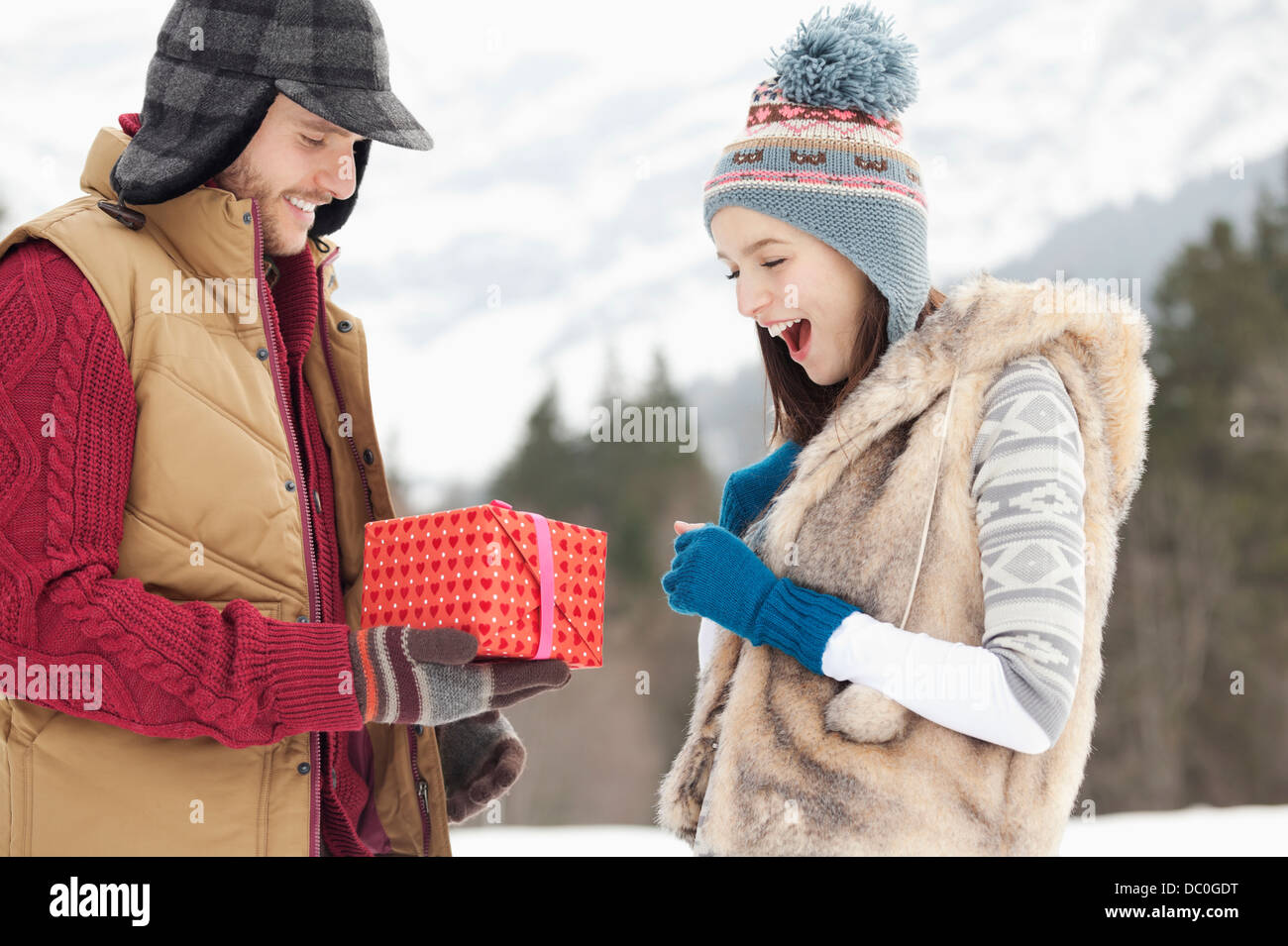 Mann Frau mit Geschenk in schneebedeckten Feld überraschend Stockfoto