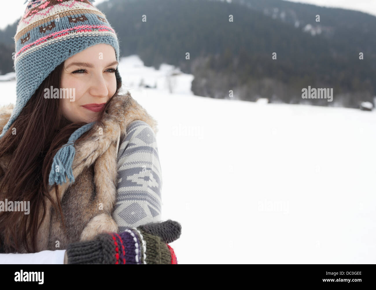 Glückliche Frau tragen stricken, Mütze und Handschuhe in schneebedecktes Feld Stockfoto