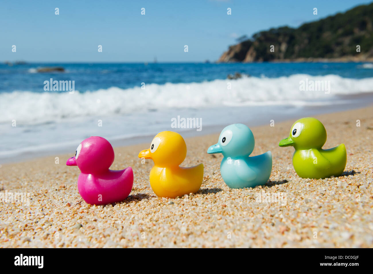 Buntes Spielzeug Enten in den Sand am Strand Stockfoto