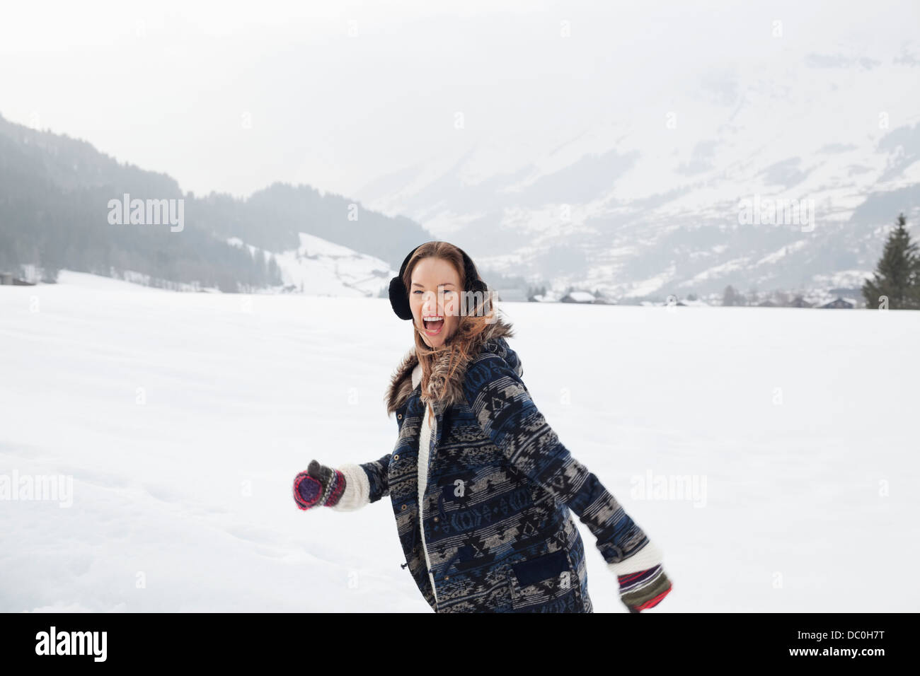 Porträt von begeisterten Frau rennt in schneebedecktes Feld Stockfoto