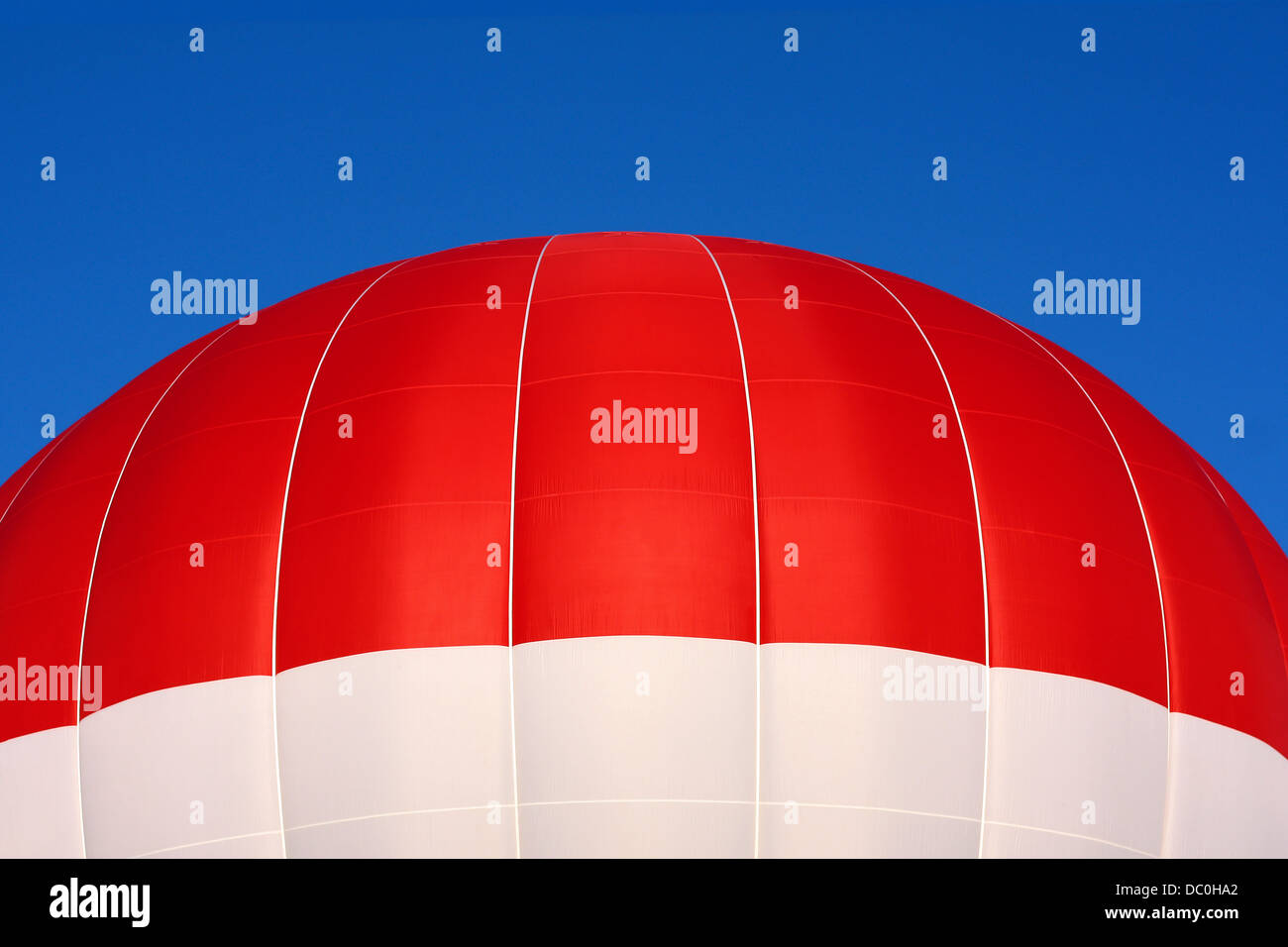 Nahaufnahme des oberen Teil des roten und weißen Heißluftballon fliegen vor einem brillanten blauen Sommerhimmel. Stockfoto
