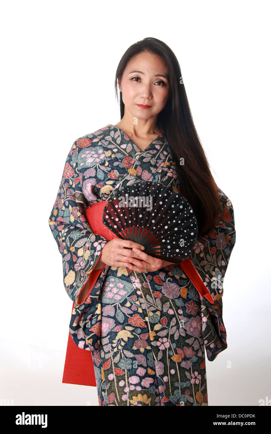 Japanerin sitzen auf dem Boden einen traditionellen blau und rot gemusterten Kimono trägt und hält ein Fan Stockfoto