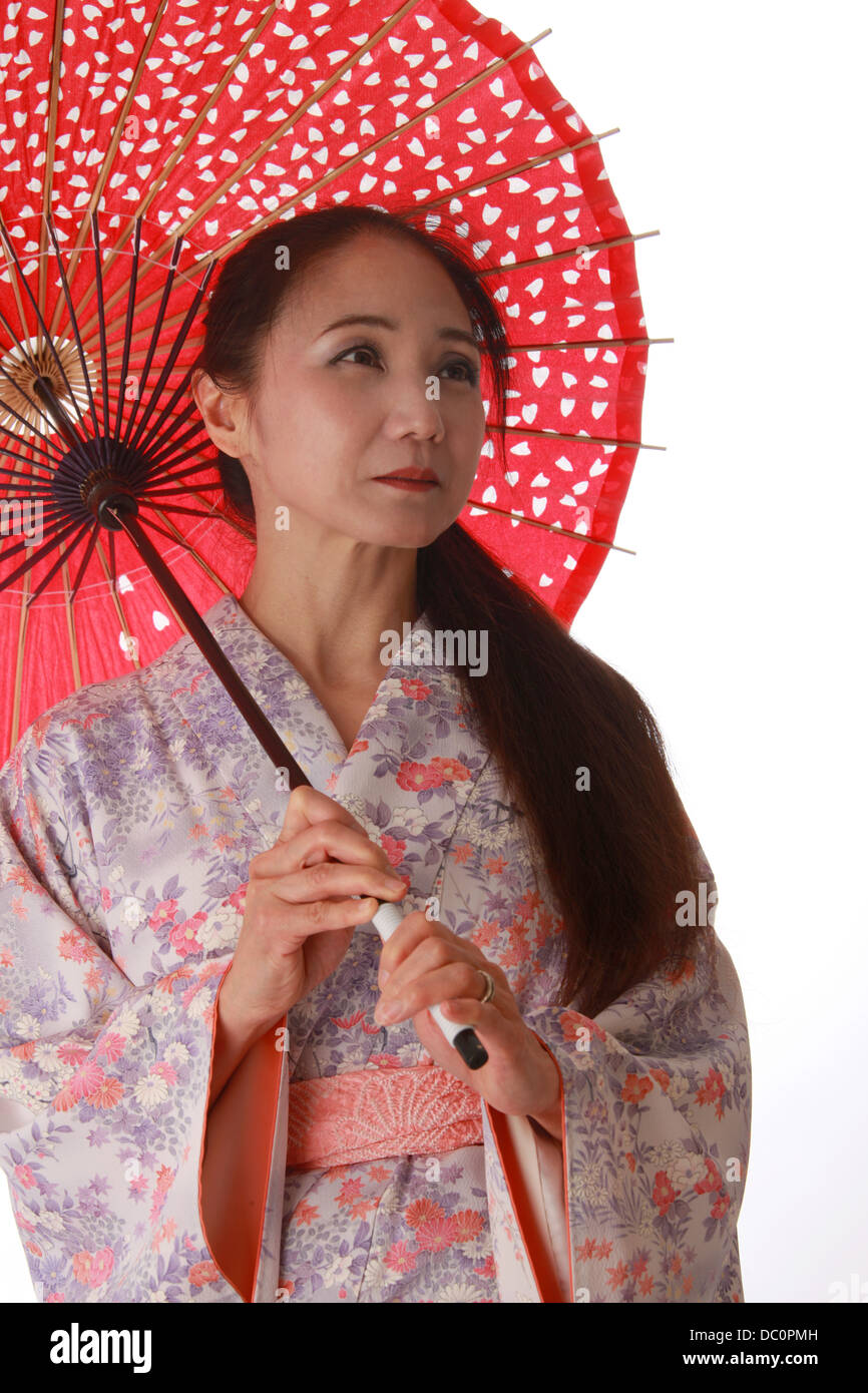 Japanische Dame trägt einen rosa und lila gemusterte Kimono und hält einen rote Sonne-Schatten. Stockfoto