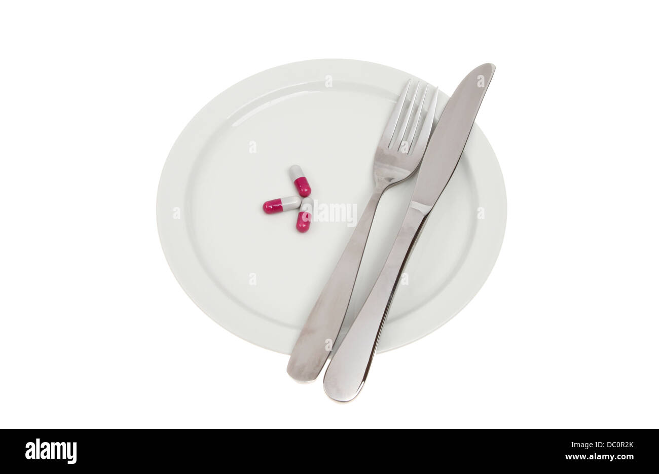 Pillen mit Messer und Gabel auf einem Teller isoliert gegen weiß Stockfoto