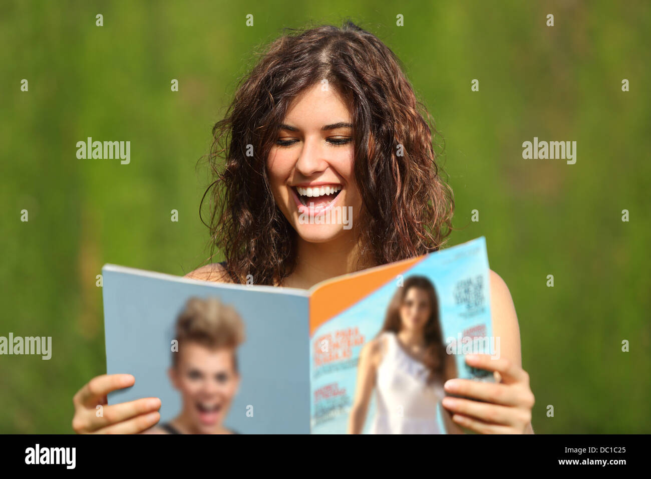 Glückliche Frau Lesen einer Zeitschrift in einem Park mit einem grünen Hintergrund Stockfoto