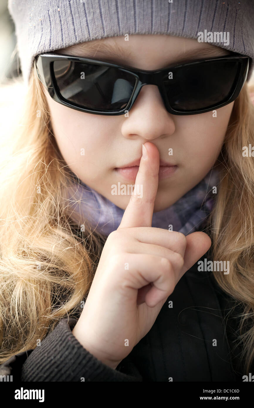 Kleine Mädchen in Sonnenbrille zeigt Stille Zeichen Stockfoto
