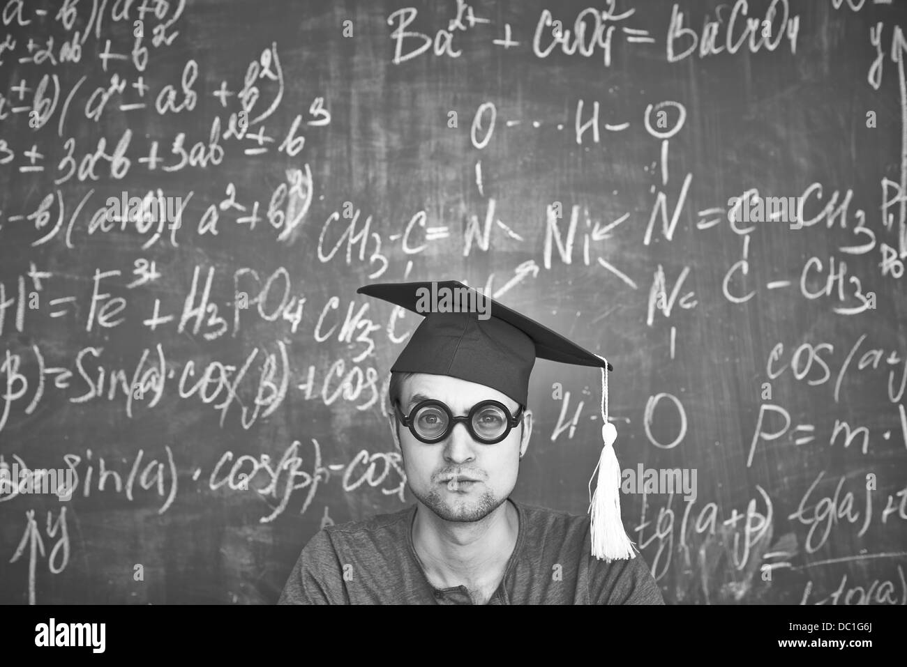 Schwarz-weiß-Bild der Schüler im Abitur Hut und Brille Blick in die Kamera auf Grund der Tafel Stockfoto