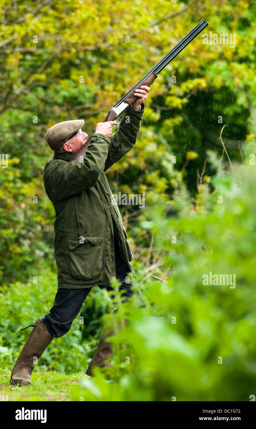 Mann auf einem simulierten Spiel schießen Ton zu schießen schießen Tweed Mütze, Ohr und Auge Verschleißschutz und stand in einem Waldgebiet Stockfoto