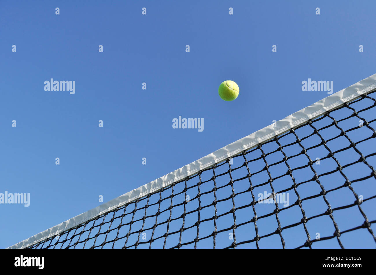 Tennisball über das Netz vor einem strahlend blauen Himmel fliegen Stockfoto