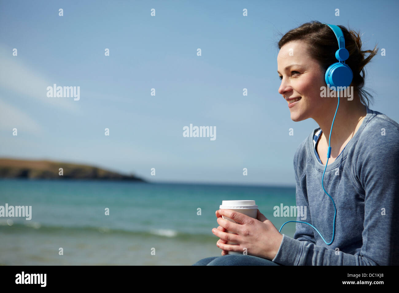 Junge Frau am Küste mit Kaffee und Kopfhörer Stockfoto