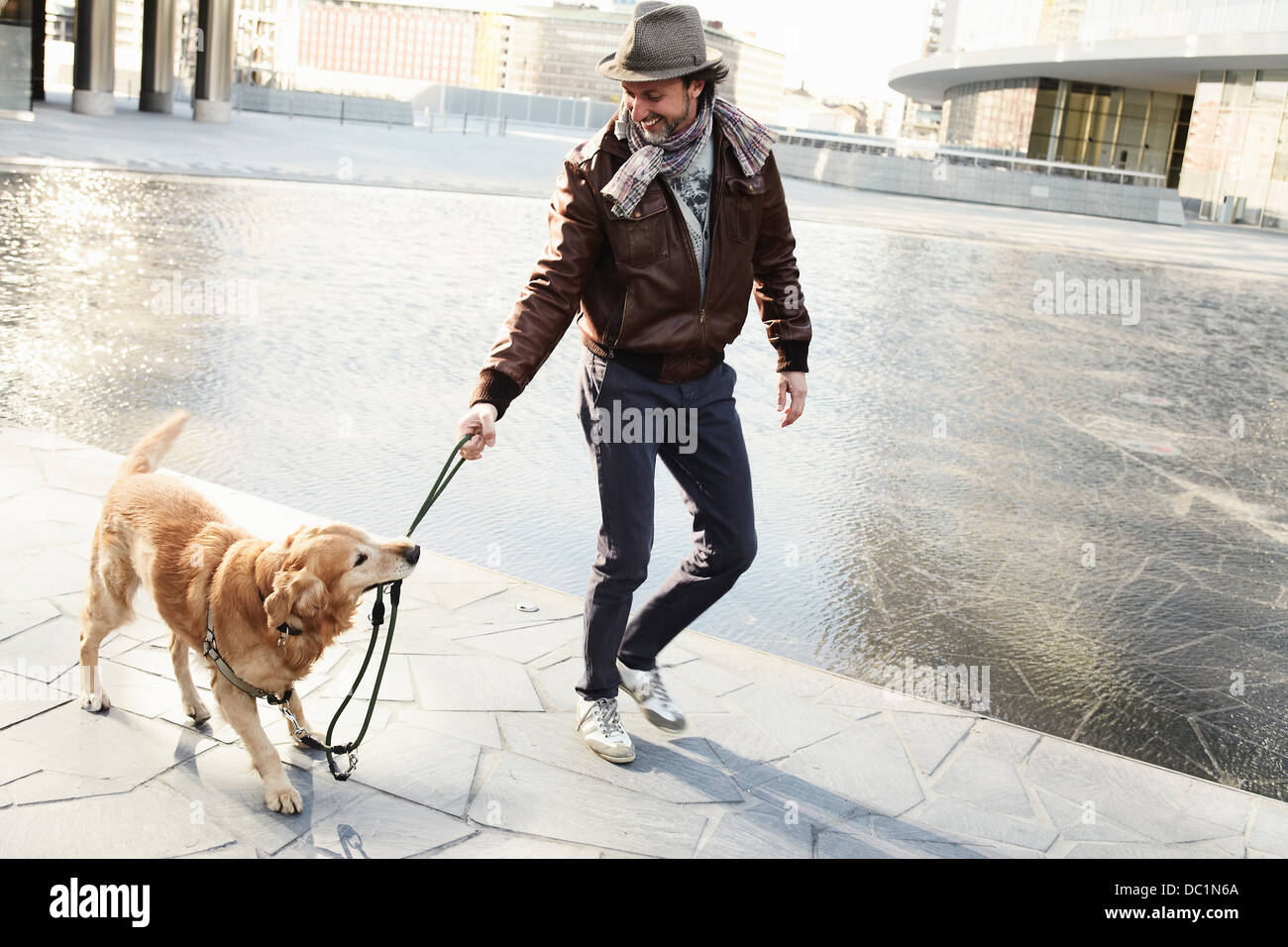 Mitte erwachsenen Mannes ziehen Leine am Hund in Stadt Stockfoto