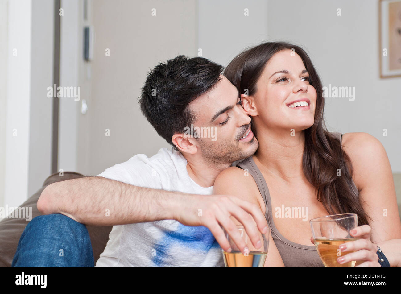 Junges Paar auf Sofa Glas Wein zu teilen Stockfoto