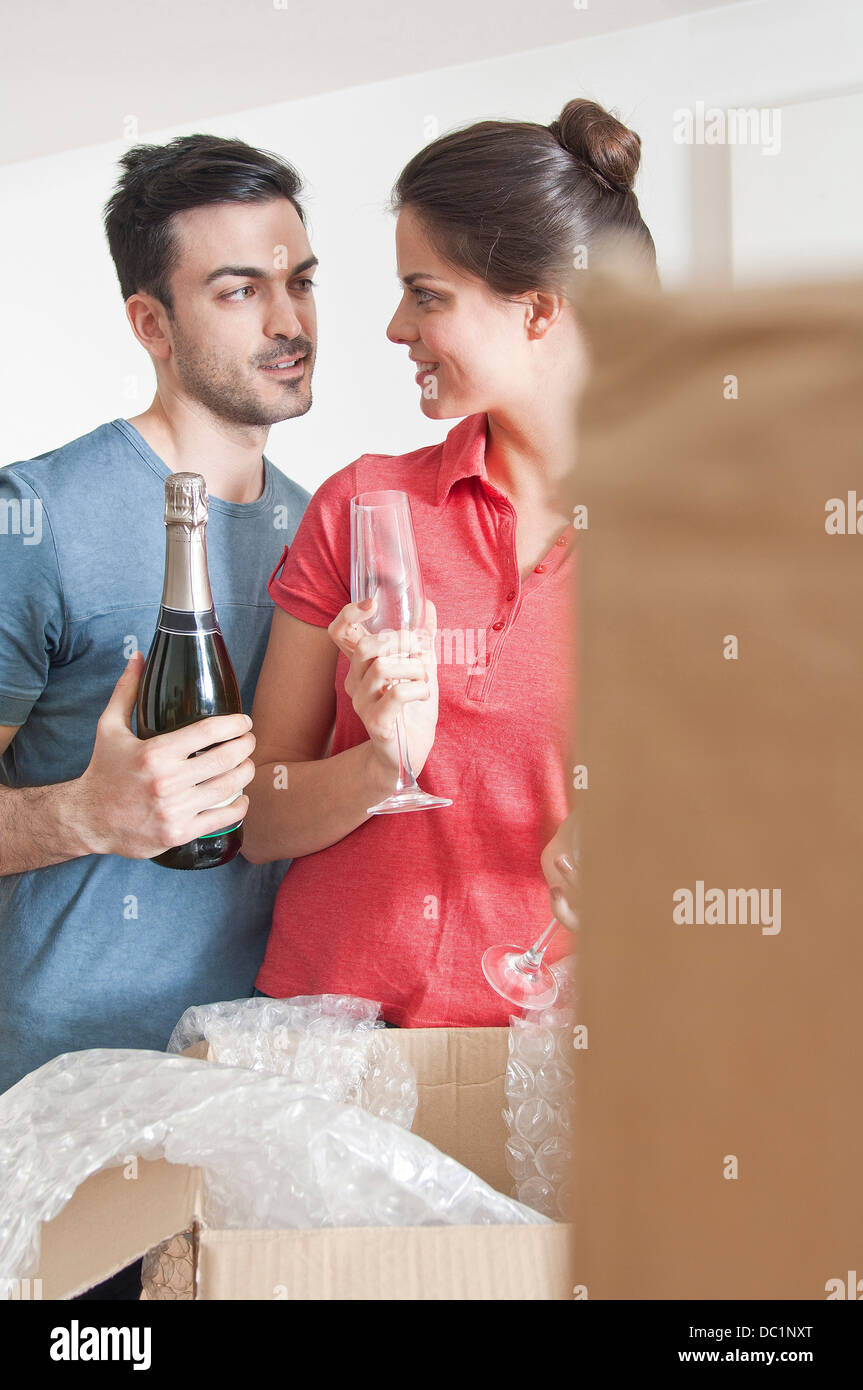 Junges Paar feiert mit Champagner unter den Kartons Stockfoto