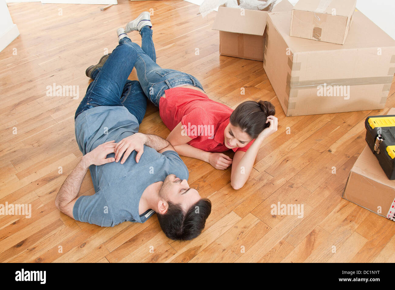 Junges Paar auf Boden unter Kartons Stockfoto