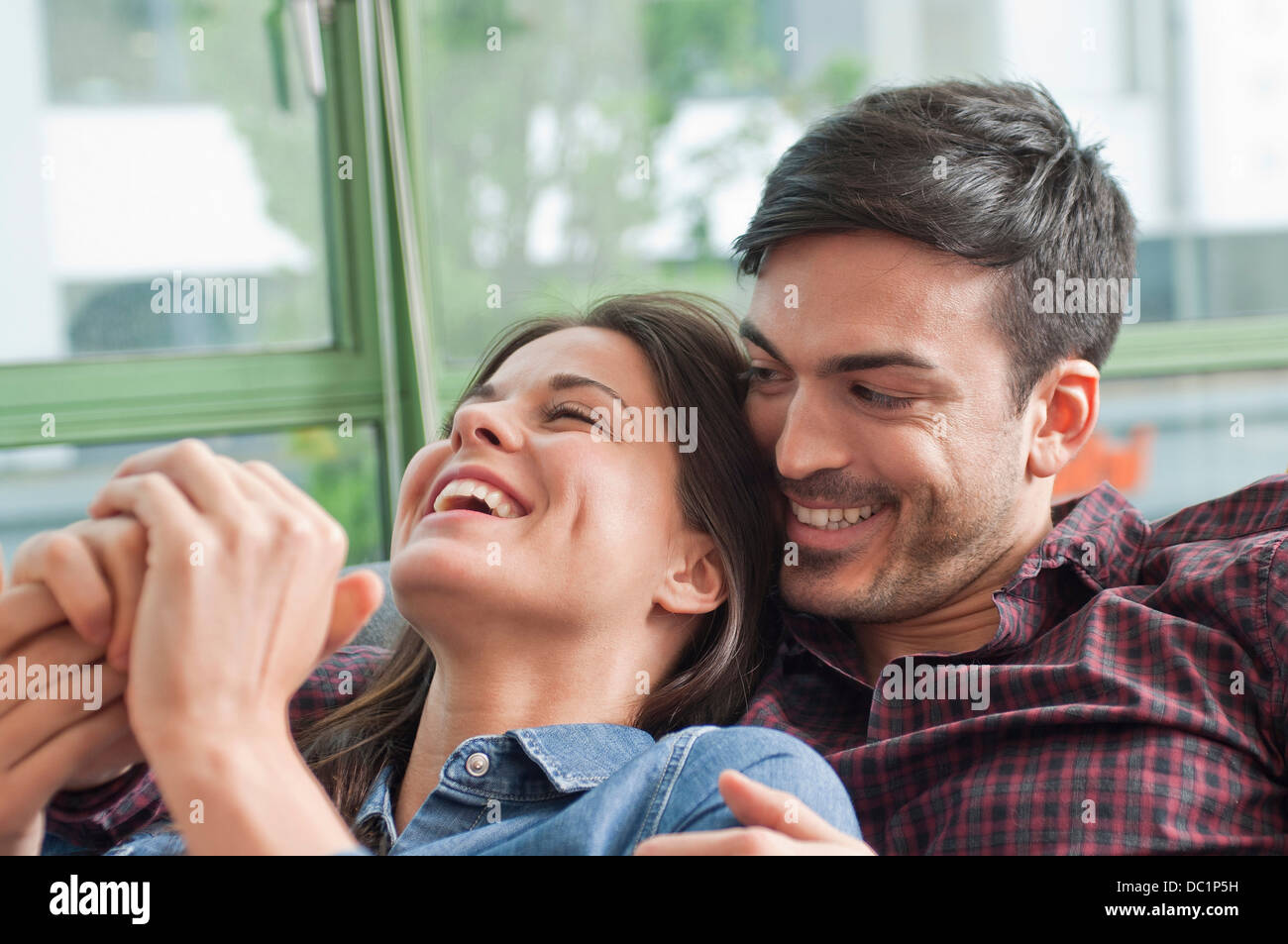 Romantische junges Paar lachend auf sofa Stockfoto
