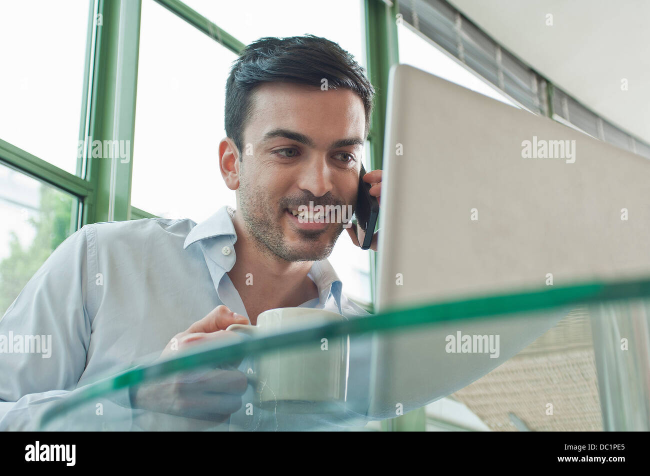 Junge männliche Büroangestellte telefonieren mit Handy Stockfoto