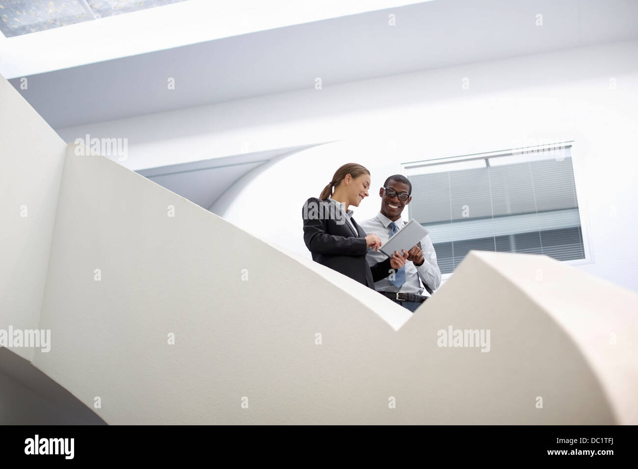 Unternehmer und Unternehmerin mit digital-Tablette auf moderne Treppe Stockfoto