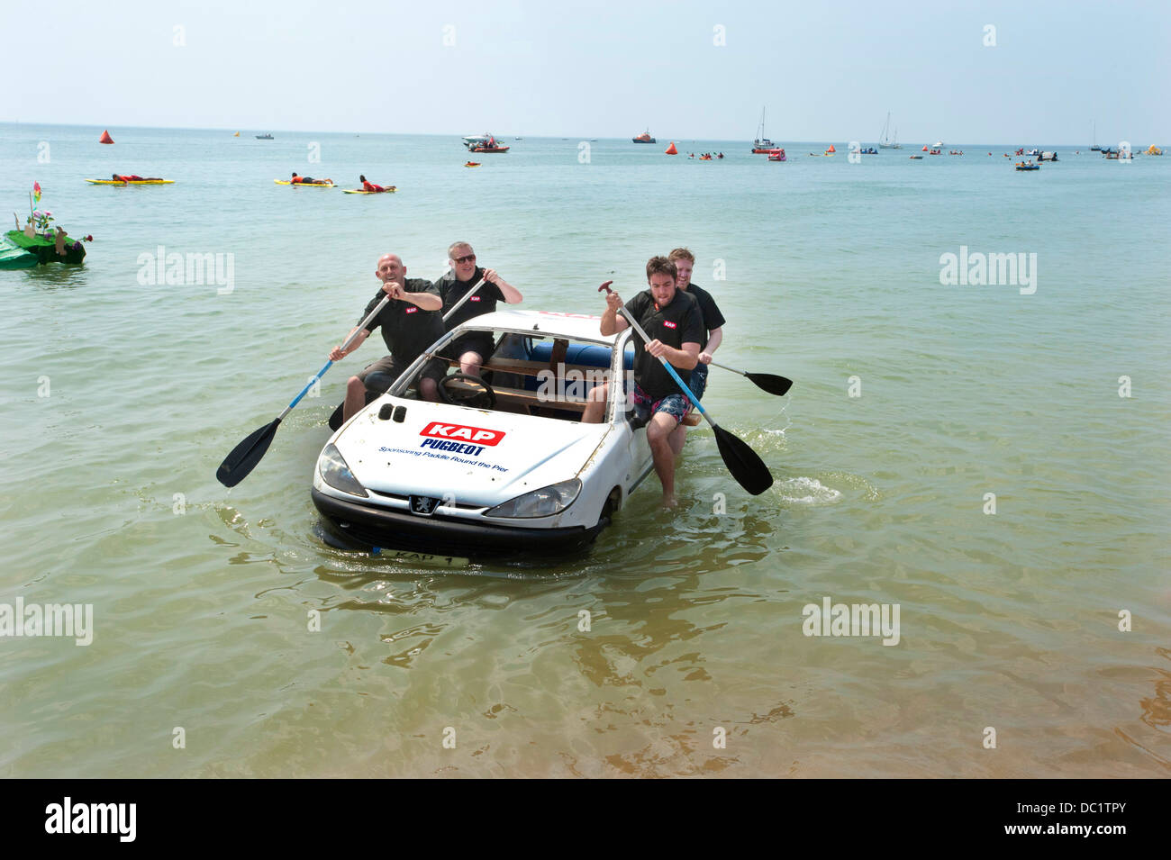Vier Männer Rudern ein Auto an Land nach dem Wettkampf in Brightons Paddle Round The Pier Wettbewerb für verrückte Handwerk. Stockfoto