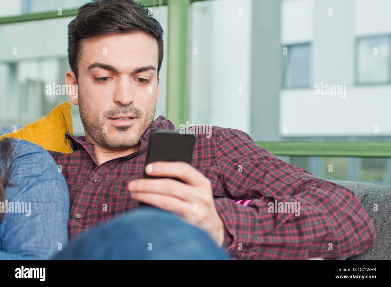 Junge Männchen zu Hause mittels Mobiltelefon Stockfoto