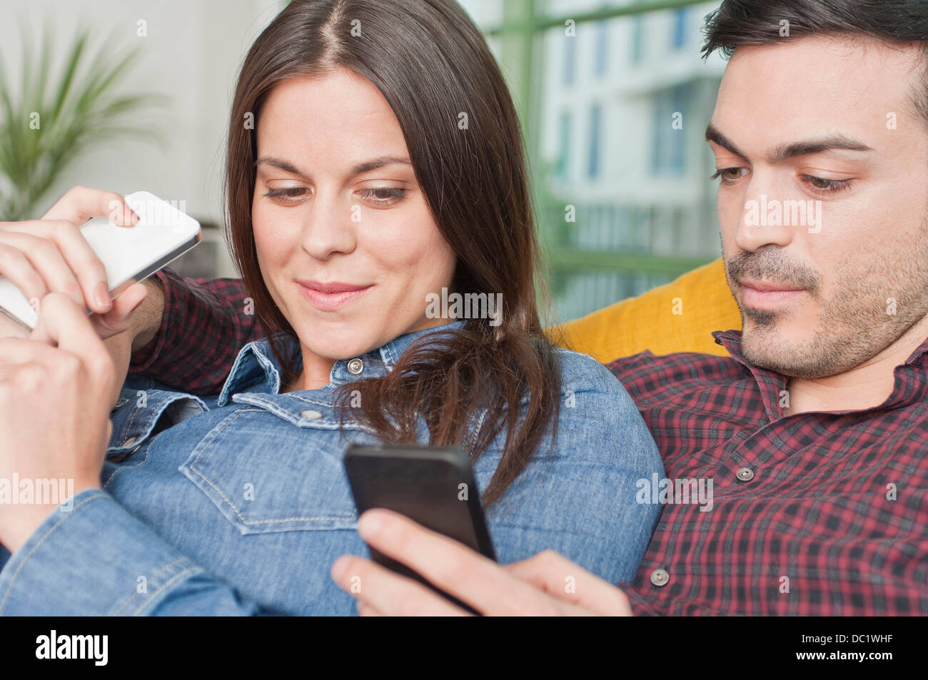 Junges Paar zu Hause mit dem Handy Stockfoto
