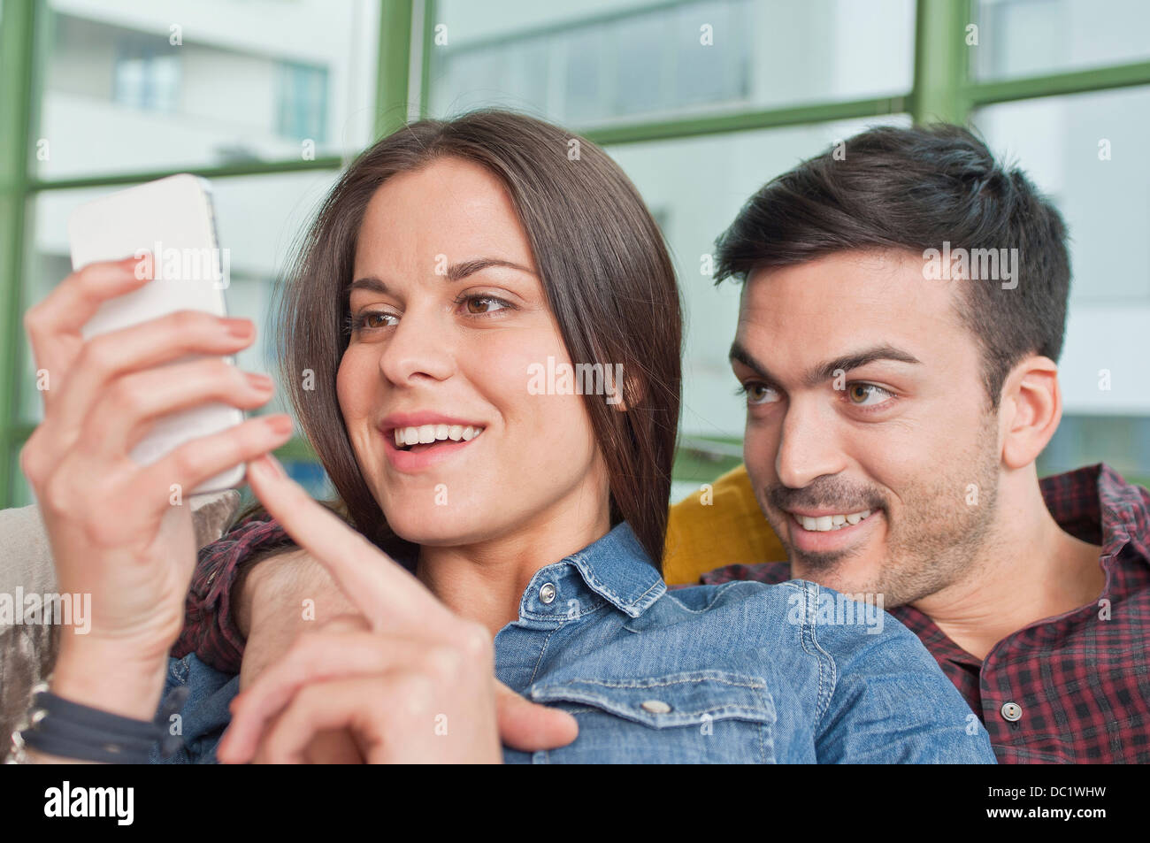 Junges Paar zu Hause Austausch Handy Stockfoto