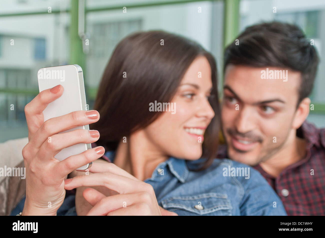 Junges Paar zu Hause mit Blick auf Handy Stockfoto