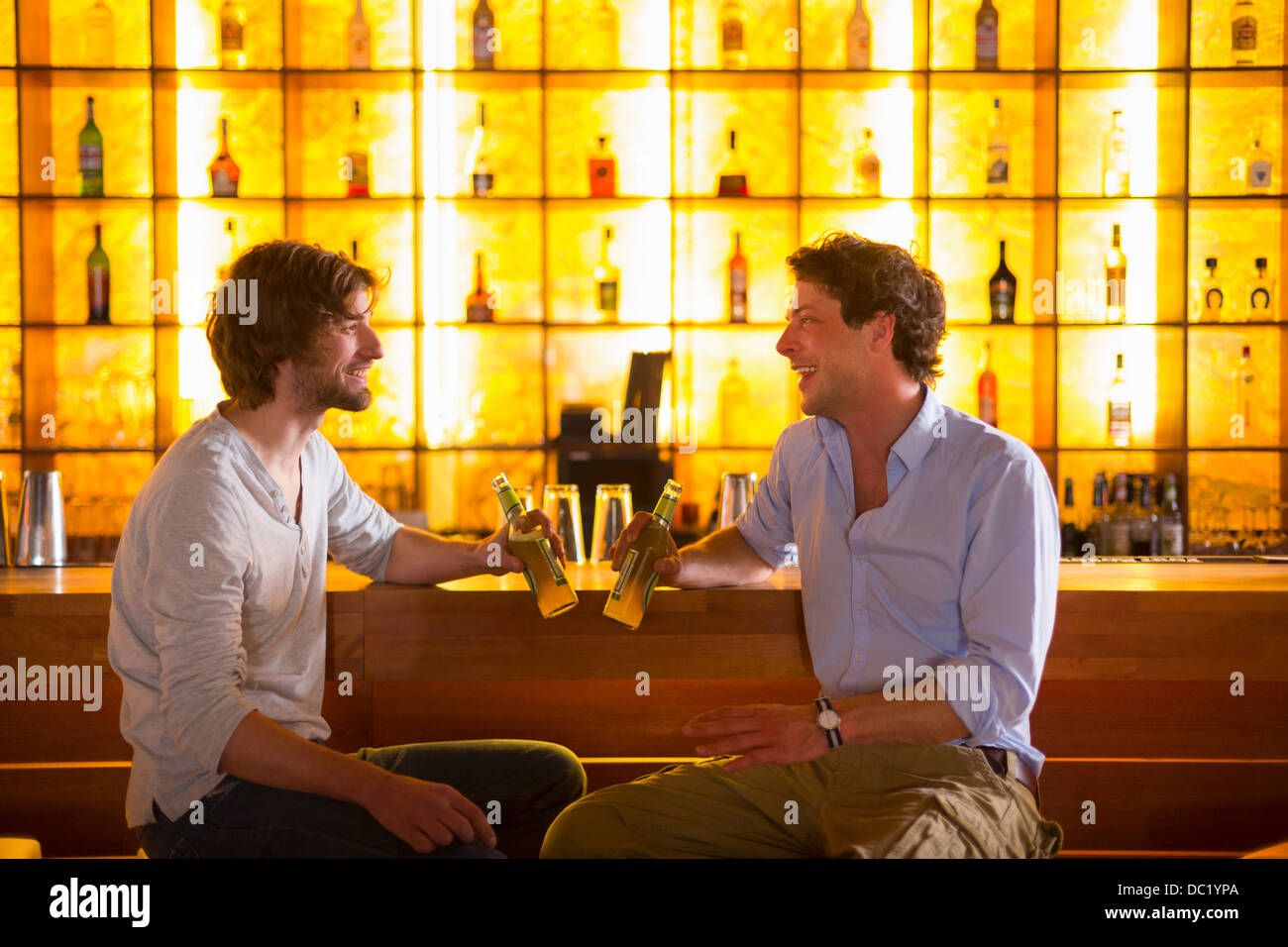 Zwei Männer sitzen an Bar mit Flaschen Bier Stockfoto