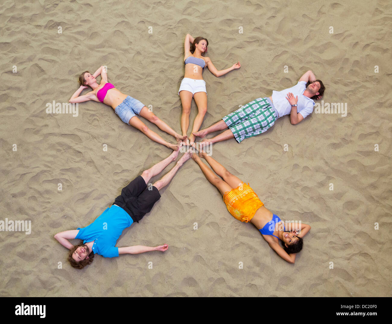 Luftaufnahme von Freunden in Sternform auf Sand liegend Stockfoto