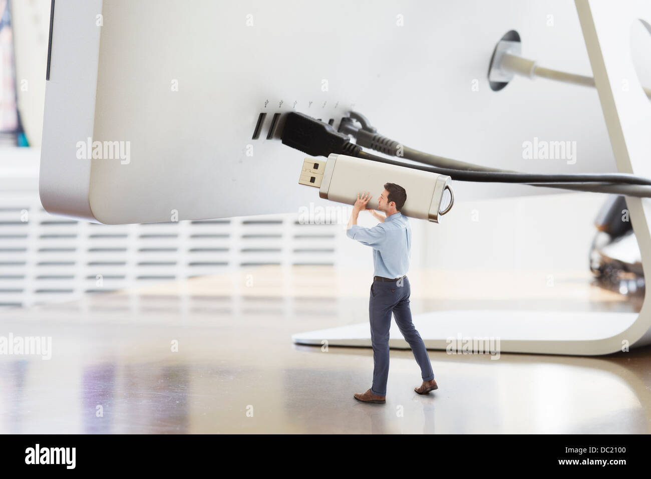 Geschäftsmann hält großen USB-Stick neben überdimensionalen Computermonitor Stockfoto