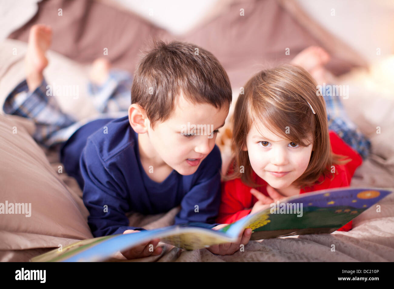 Zwei kleine Kinder auf Bett Bilderbuch betrachten Stockfoto
