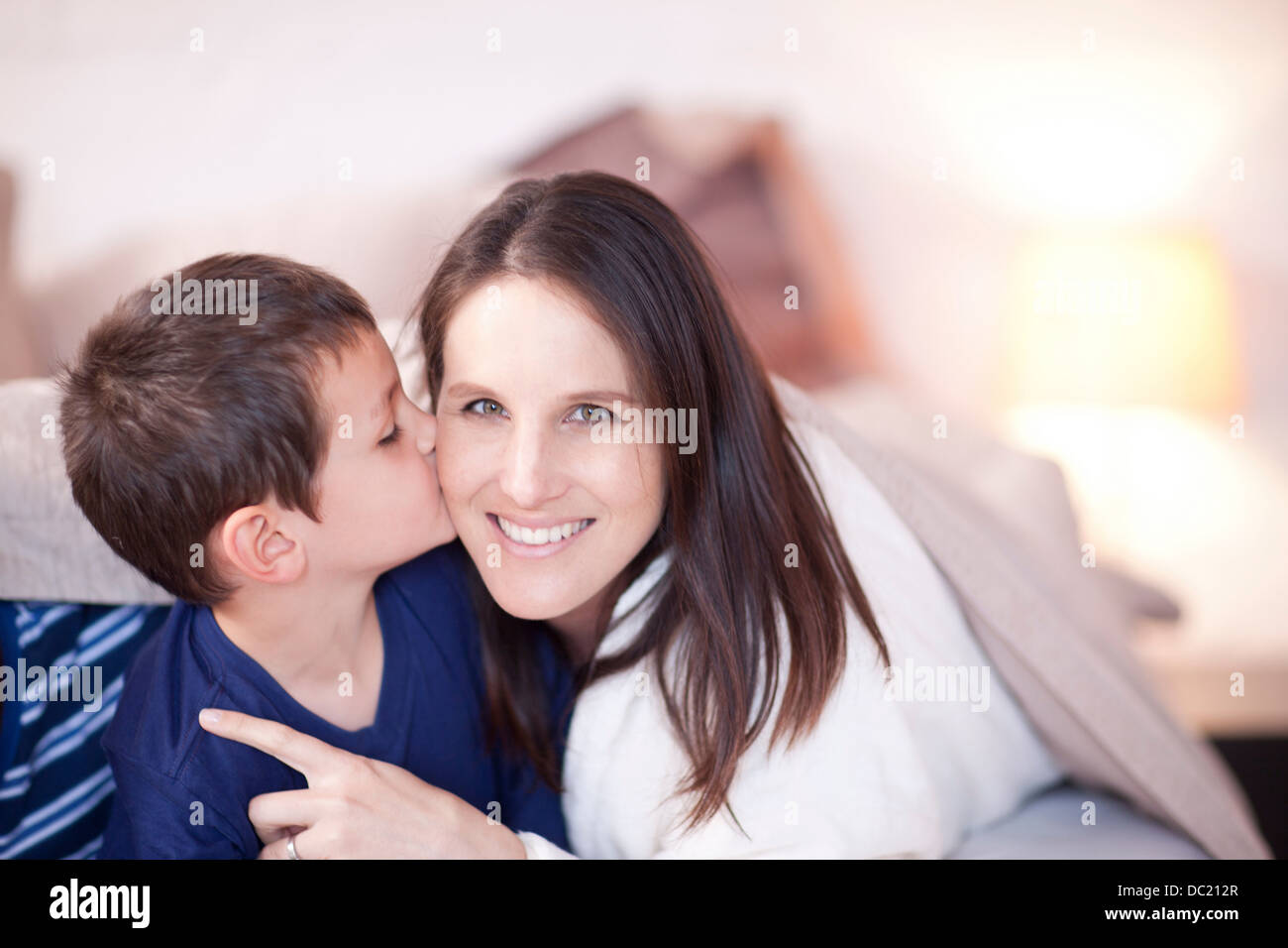 Sohn, küssen Mütter Wange unter Bettdecke Stockfoto