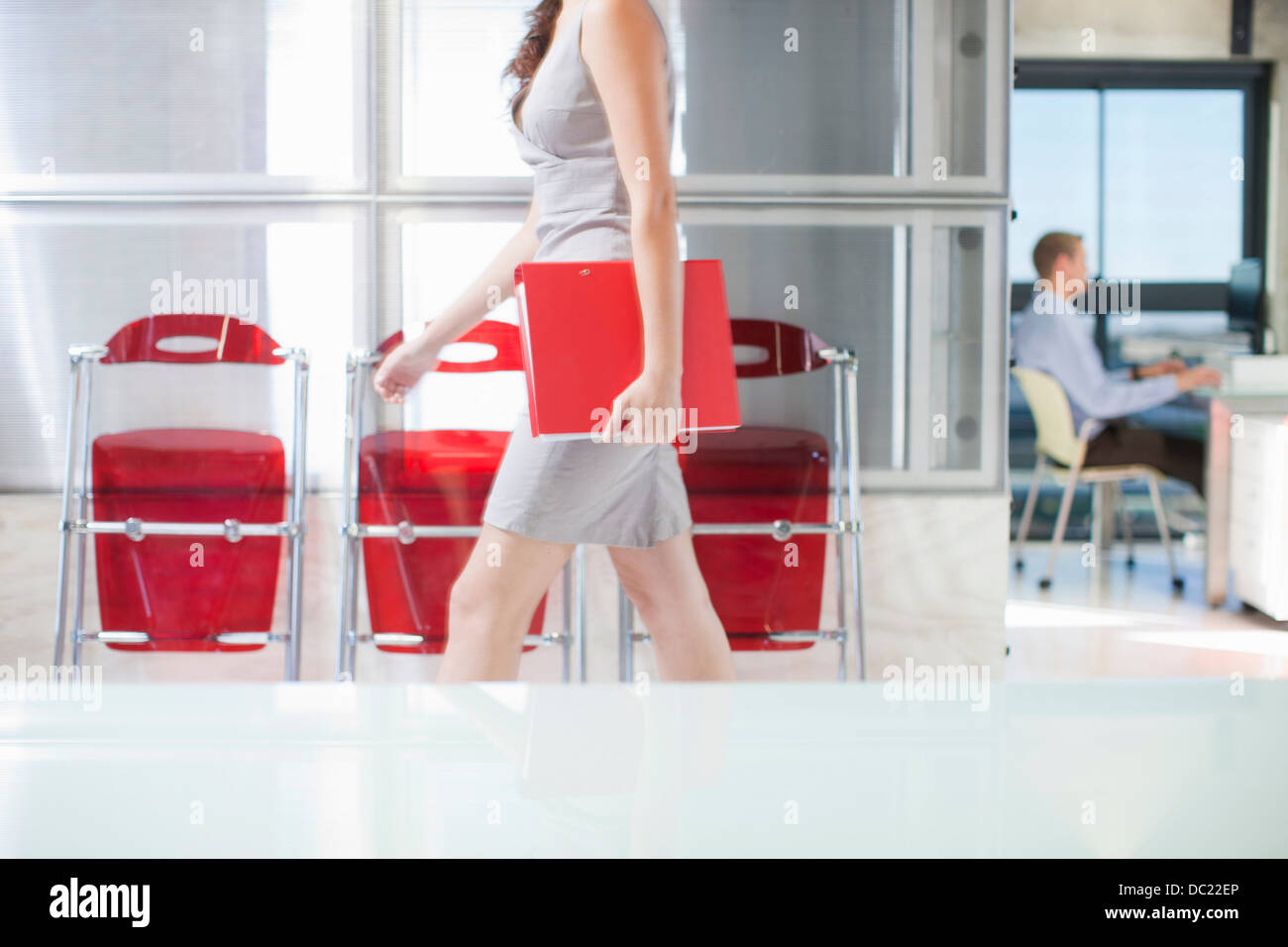 Junge Frau, die zu Fuß durch Büro Stockfoto