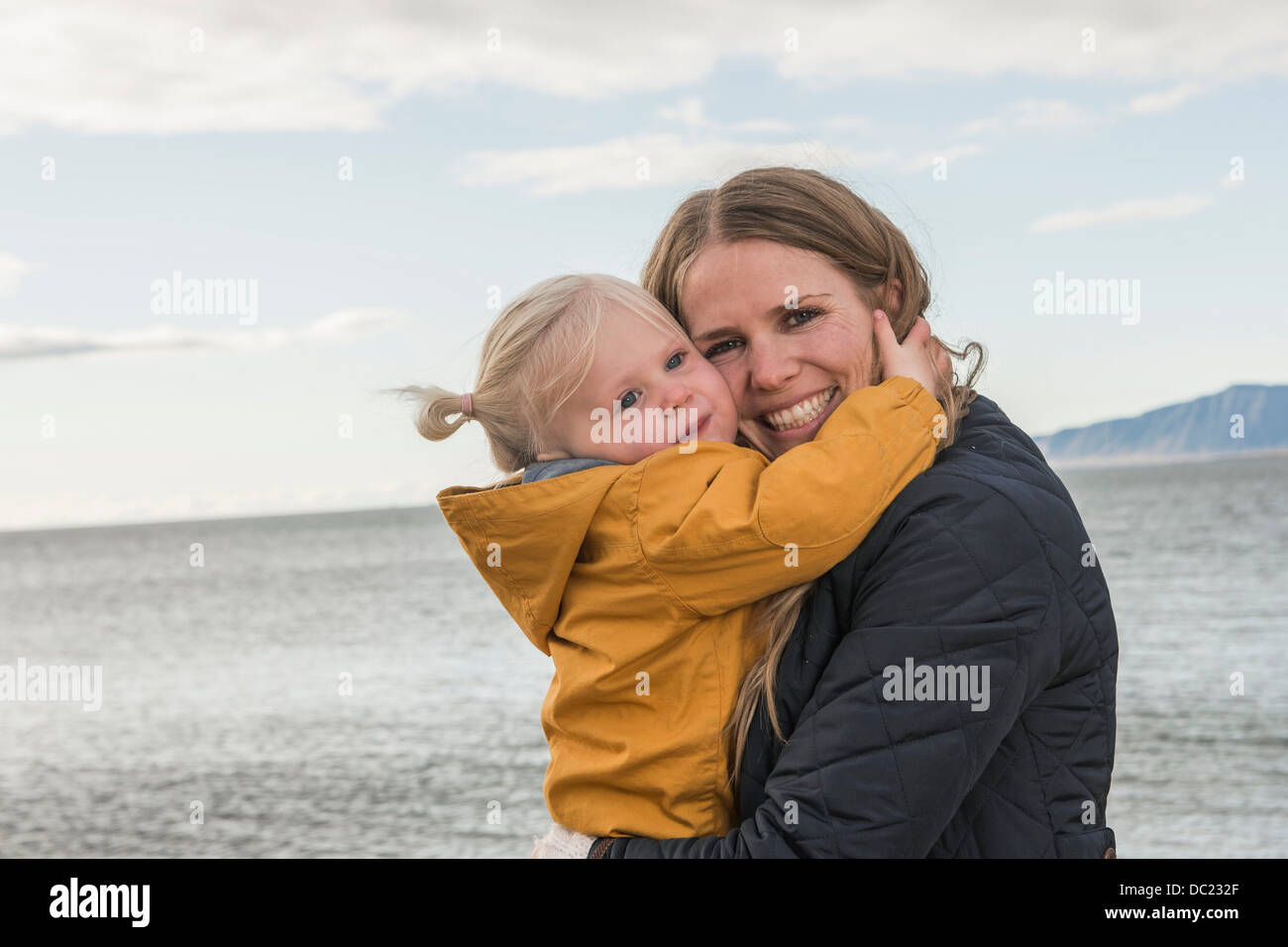 Mutter und Kleinkind an Küste umarmt Stockfoto
