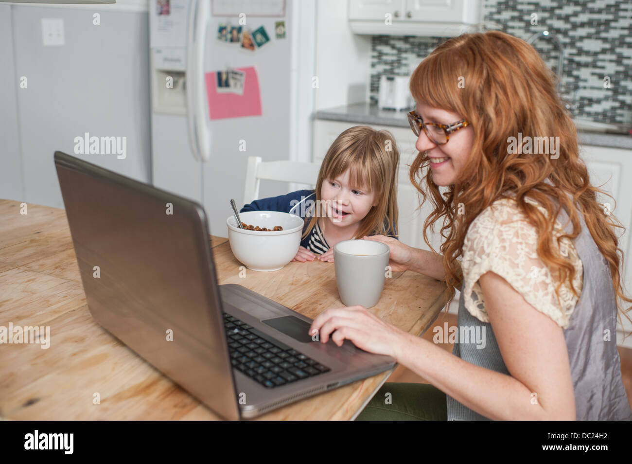 Mutter und Tochter beim Frühstück und mit laptop Stockfoto