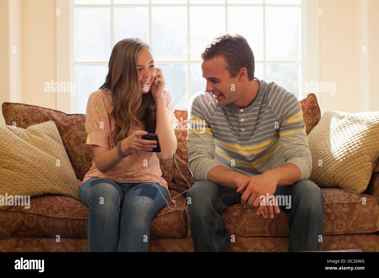 Bruder und Schwester auf Sofa mit Kopfhörer Stockfoto