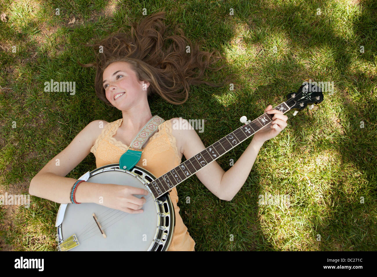 Teenager-Mädchen spielen Banjo auf dem Rasen, Draufsicht Stockfoto