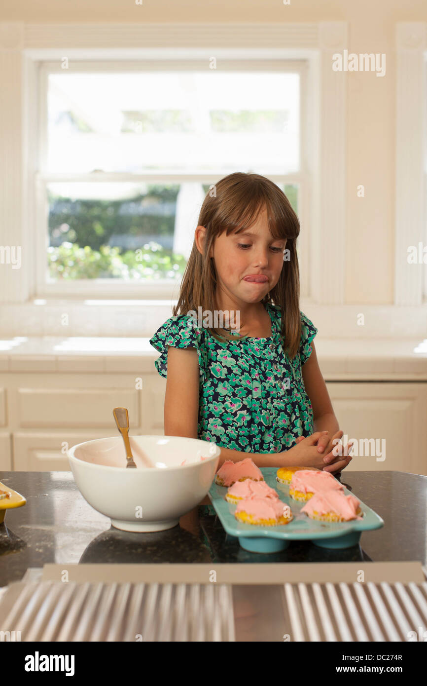 Junges Mädchen Blick auf Muffins, Lippen lecken Stockfoto